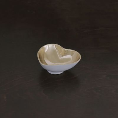 White ceramic heart-shaped mini bowl with champagne gold metallic accents on a neutral background
