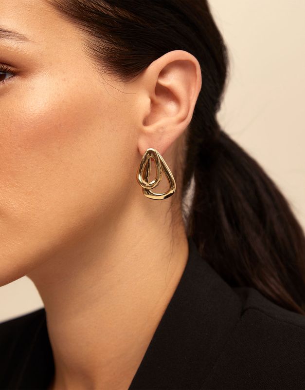 Gold-plated Connected Earrings by Uno de 50 worn in a lifestyle setting, showcasing the geometric linked design against skin tone