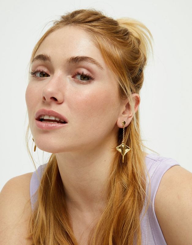 Uno de 50 Ser Majestuosa manta ray drop dangle earrings worn in a lifestyle setting, showcasing the sculptural metal design and hanging movement of the statement piece.