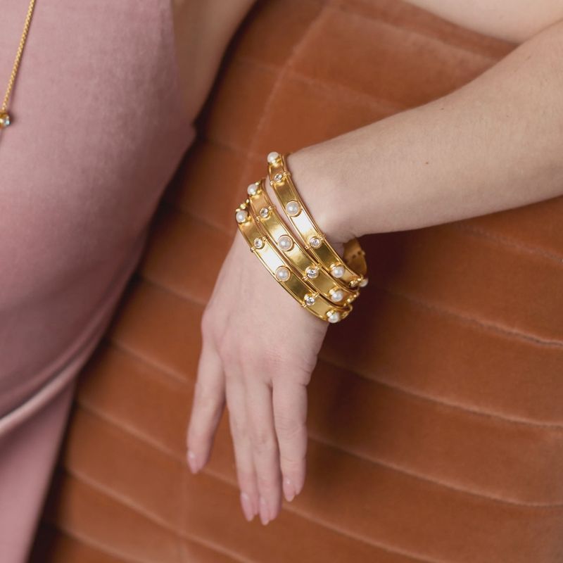 Julie Vos Tribeca bangle in 24K gold plate with pearl and cubic zirconia stones worn on wrist in lifestyle setting