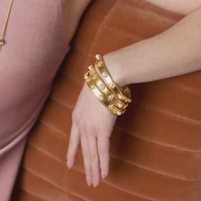 Julie Vos Tribeca bangle in 24K gold plate with pearl and cubic zirconia stones worn on wrist in lifestyle setting