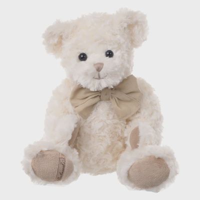 Noah cream plush bear with tan bow, shown against a white background in studio lighting