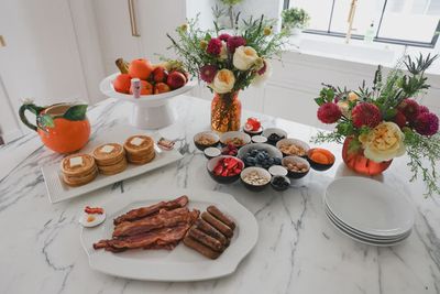 Nora Fleming pinstriped stoneware serving dish in a table setting with place settings and fresh flowers.