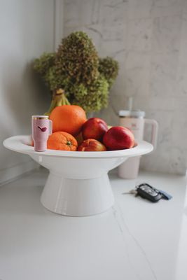 Nora Fleming Sip Happens mini drink holder in a lifestyle setting, showing the small ceramic vessel designed to hold beverages or condiments.