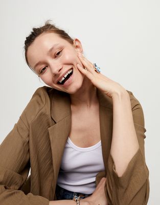 Large blue oval crystal ring from Uno de 50 worn on hand against neutral background