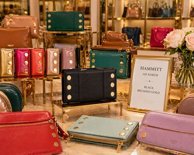 Hammitt 110 North black brushed gold wallet displayed in colorful luxury boutique with vibrant leather accessories