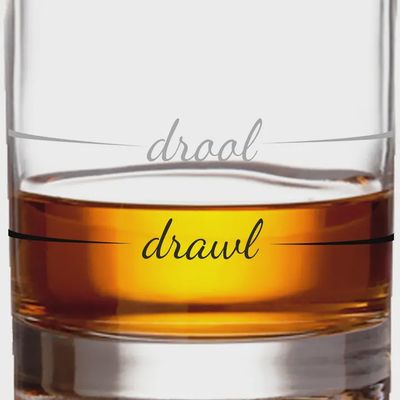Clear glass whiskey measuring cup with etched measurement lines and Drool to Drawl branding on white background