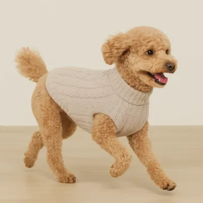 Stone-colored cable knit pet sweater from Barefoot Dreams draped over a chair in a cozy home setting