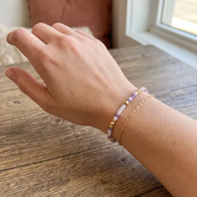 Purple and white beaded bracelet with 14k gold-filled accents styled on wrist in lifestyle setting