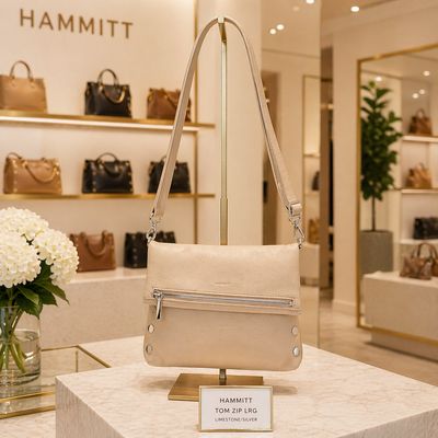 Hammitt Tom Zip Lrg limestone leather crossbody with silver hardware displayed in a luxury retail store