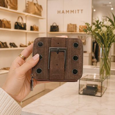Close-up of Hammitt 5 North belted suede gunmetal wallet held in boutique store with luxury handbags in background