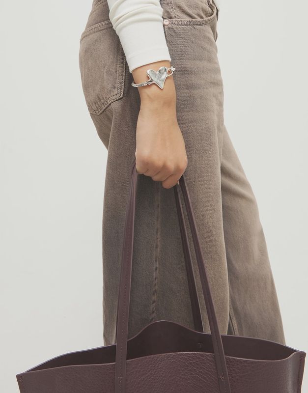 Uno de 50 Palpito semi-rigid hinged heart bracelet worn on wrist, showcasing the articulated heart design and metallic finish