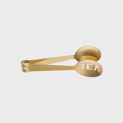 Stainless steel tea bag tongs with a string slot, displayed against a neutral background in studio lighting