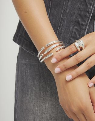 Uno de 50 Roots bangle bracelet with intertwined organic shapes worn on wrist in lifestyle setting