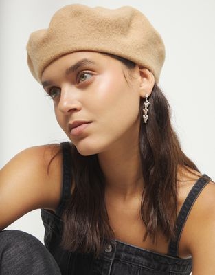 Uno de 50 Chained Hearts Drop Earrings in gold-tone metal with linked heart charms dangling from chain, worn in a lifestyle setting.