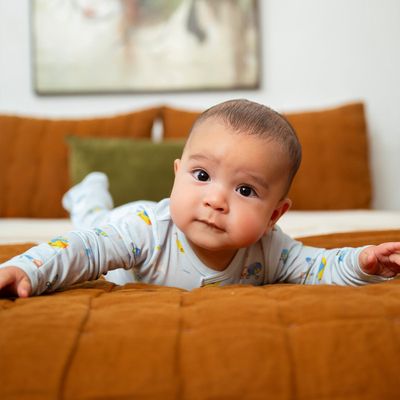 Infant in Magnetic Me TENCEL modal footie pajamas with attached mitten cuffs and grippy feet, photographed in a lifestyle setting.