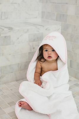 Pink hooded baby towel and matching washcloth from 3 Marthas, displayed in a lifestyle setting with soft textures and natural lighting