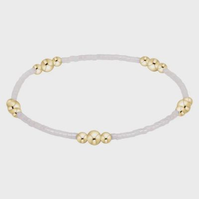 Gold Hope Purpose bracelet with silky white beads on a neutral background, studio shot