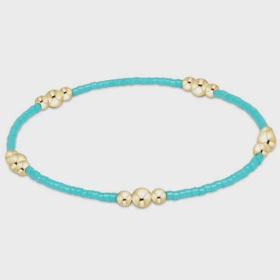 Gold-toned beaded bracelet with turquoise stones arranged in a linear pattern on a neutral background