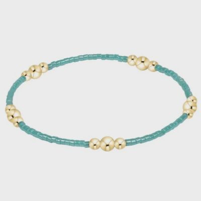 Gold beaded bracelet with sea glass stone centerpiece on white background