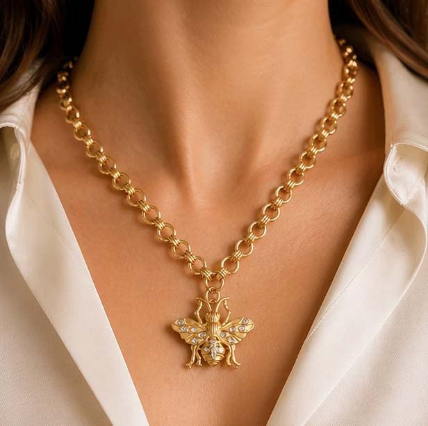 Close-up of gold bee pendant necklace by French Kande on woman’s neck with Brittany chain detail
