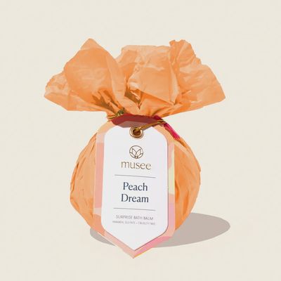 Musee Peach Dream bath balm in soft peachy-pink tone, isolated on white background, with visible keychain surprise visible inside