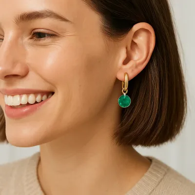Gold huggie hoop earring with small charm detail worn in lifestyle setting, measuring 0.5 inches