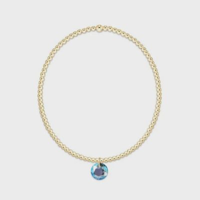 Gold beaded bracelet with 2mm spheres and a March Reflection charm on a neutral background