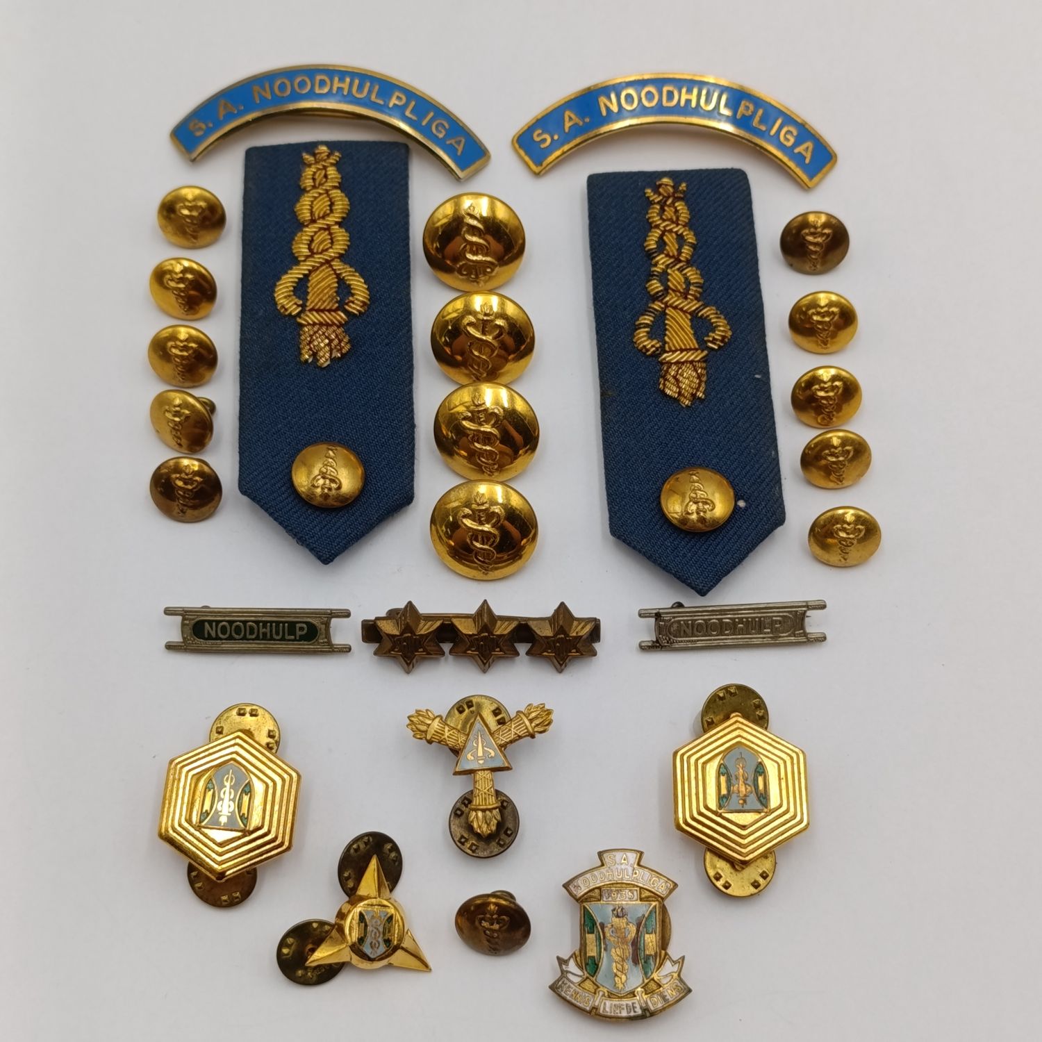 Collection of SA Noodhulp-liga badge and bottons