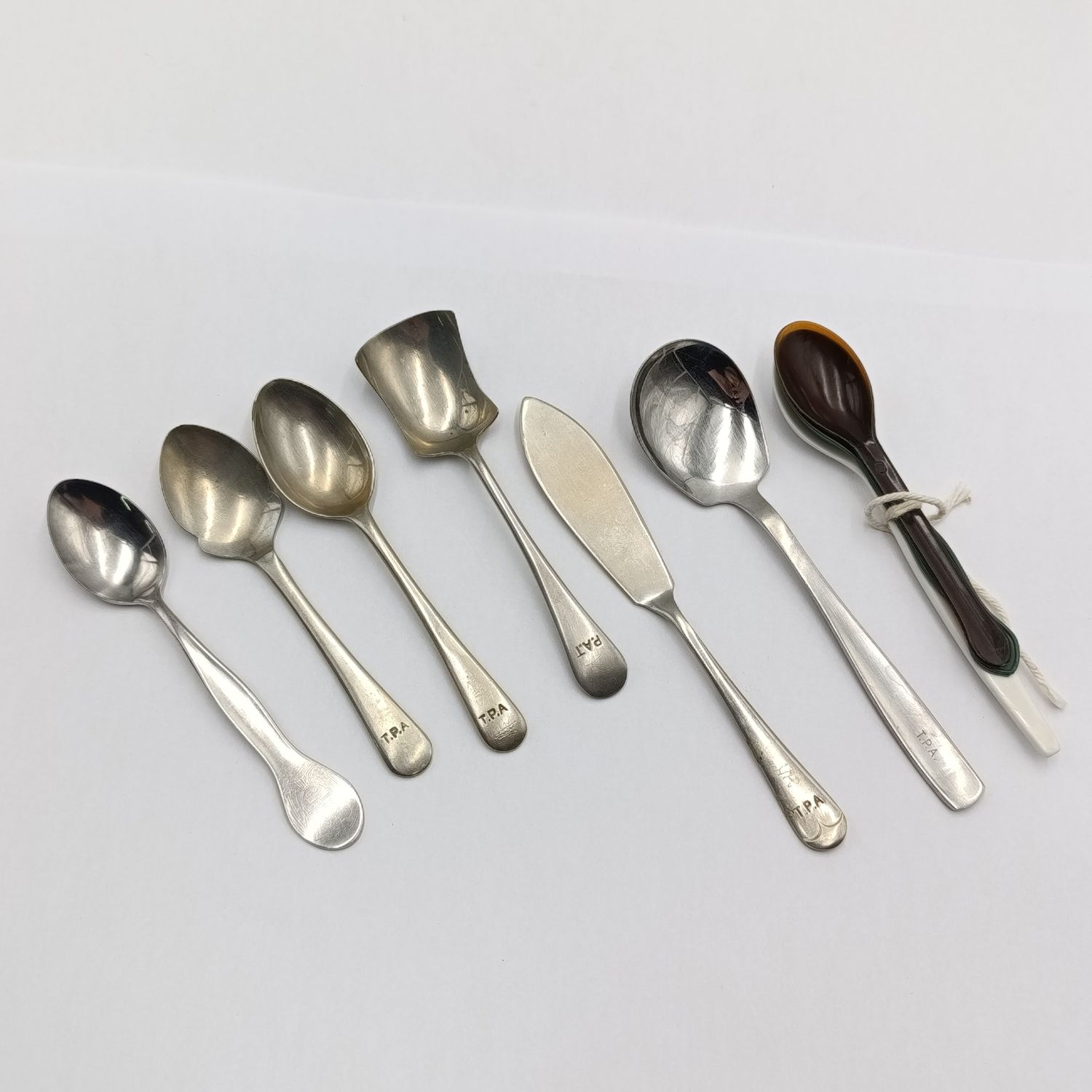 Set of spoons depicting the history of Transvaal Provincial Administration hospitals catering department - 6 metal and 3 plastic types - ons sugar spoon with wrongspelling of TPA (Pat)