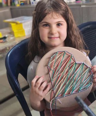 Young girl proudly holding her completed colorful FaceLyne string art kit