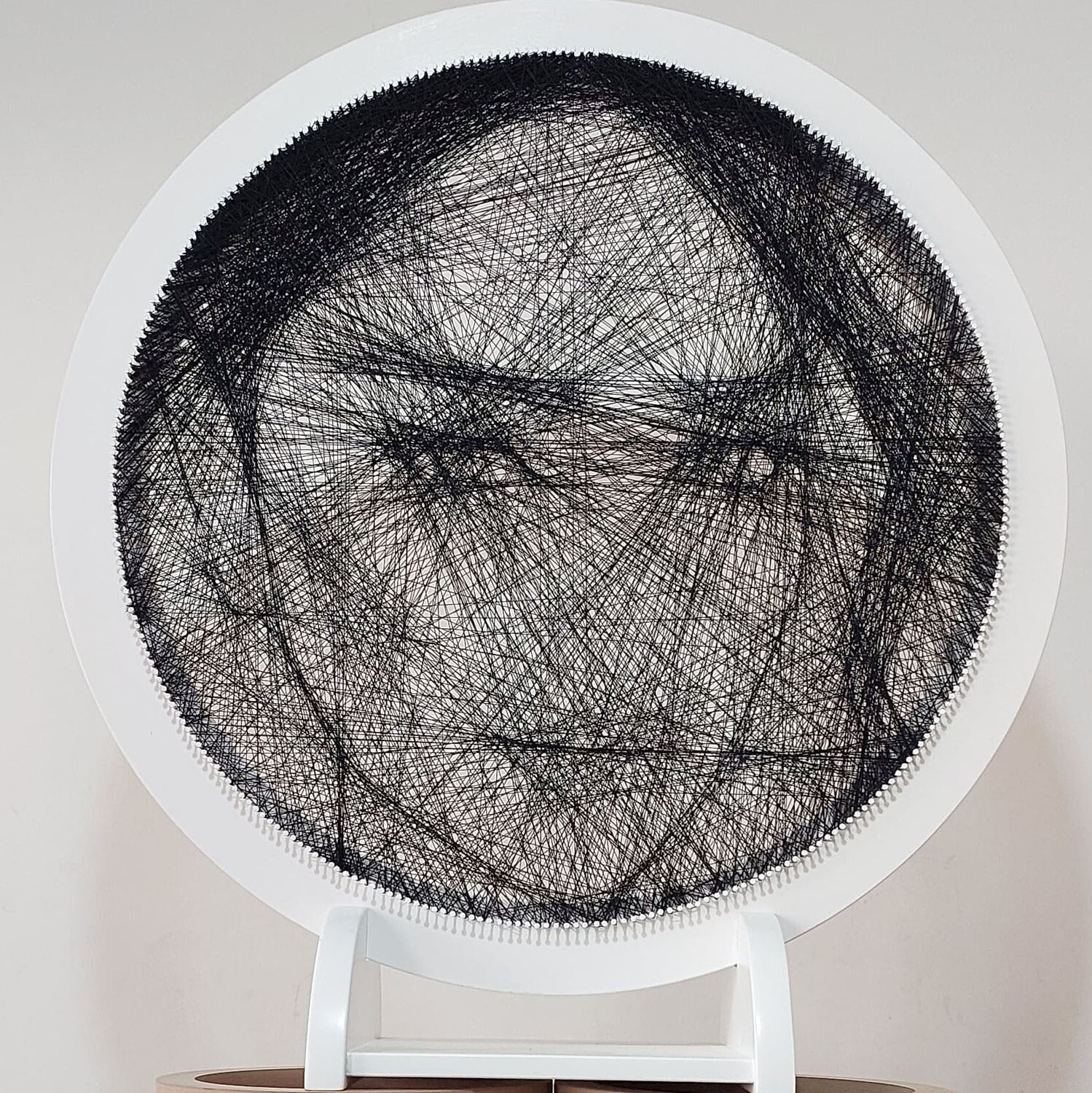 Close-up of a custom woman’s portrait handcrafted from black threads