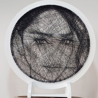 Close-up of a custom woman’s portrait handcrafted from black threads