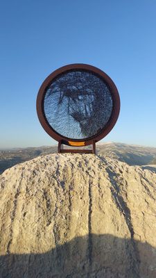 Royale circular string art portrait displayed outdoors on a rocky landscape