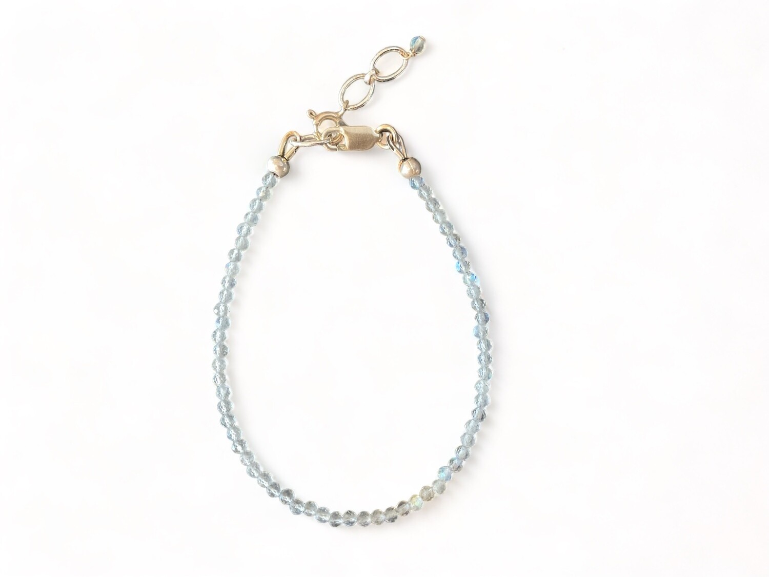 This unique bracelet features tiny 2mm micro-faceted labradorite beads that shimmer with a play of colors, ranging from blue to green. It is designed to help support magic and transformation, with a sterling silver clasp and a 1-inch extender chain for adjustable fit.