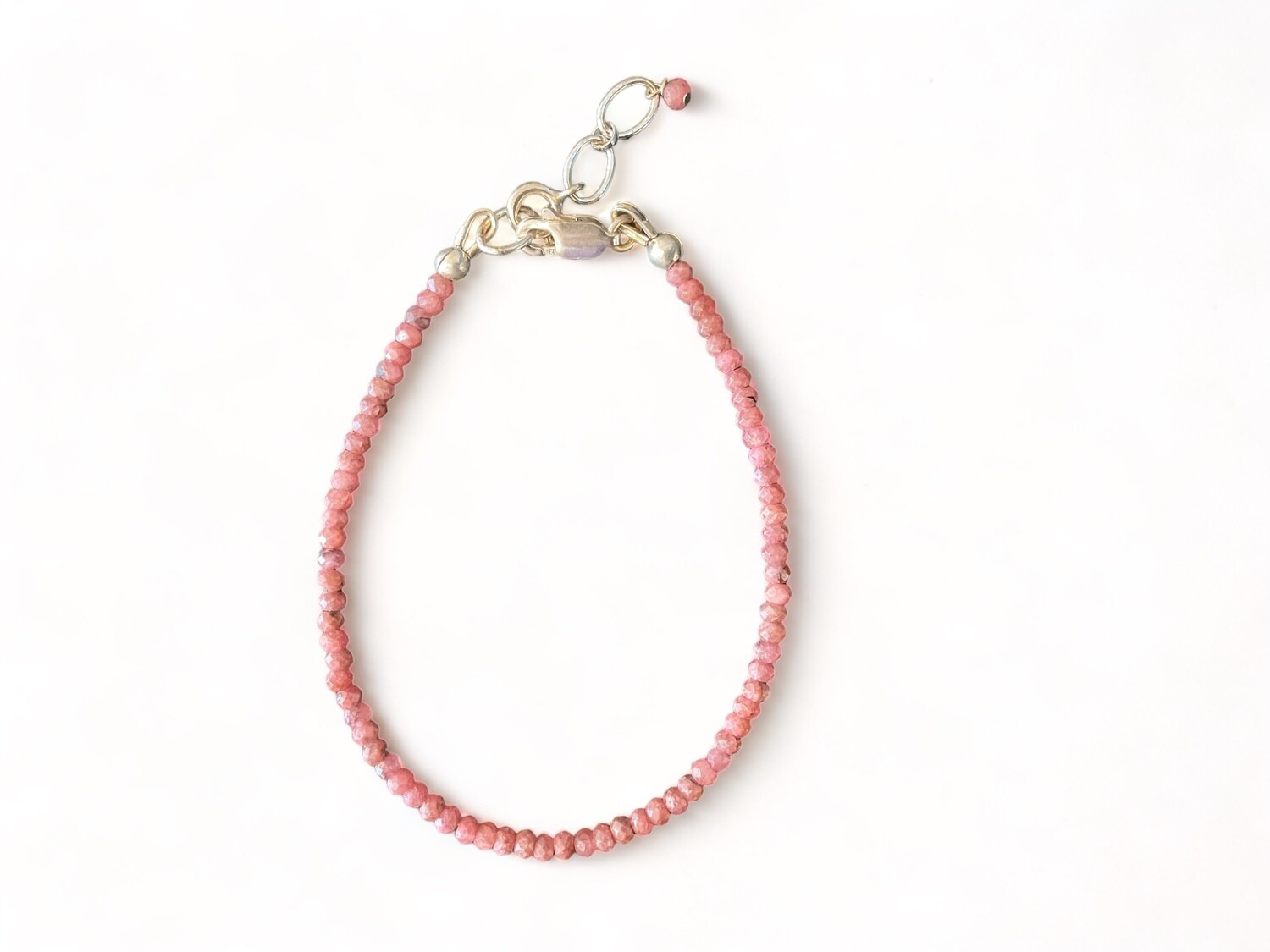 Photo of a Rhodochrosite Micro Faceted Bracelet with small, pink beads and a sterling silver clasp. The bracelet includes a 1-inch extender chain and measures 6.5 inches in length.