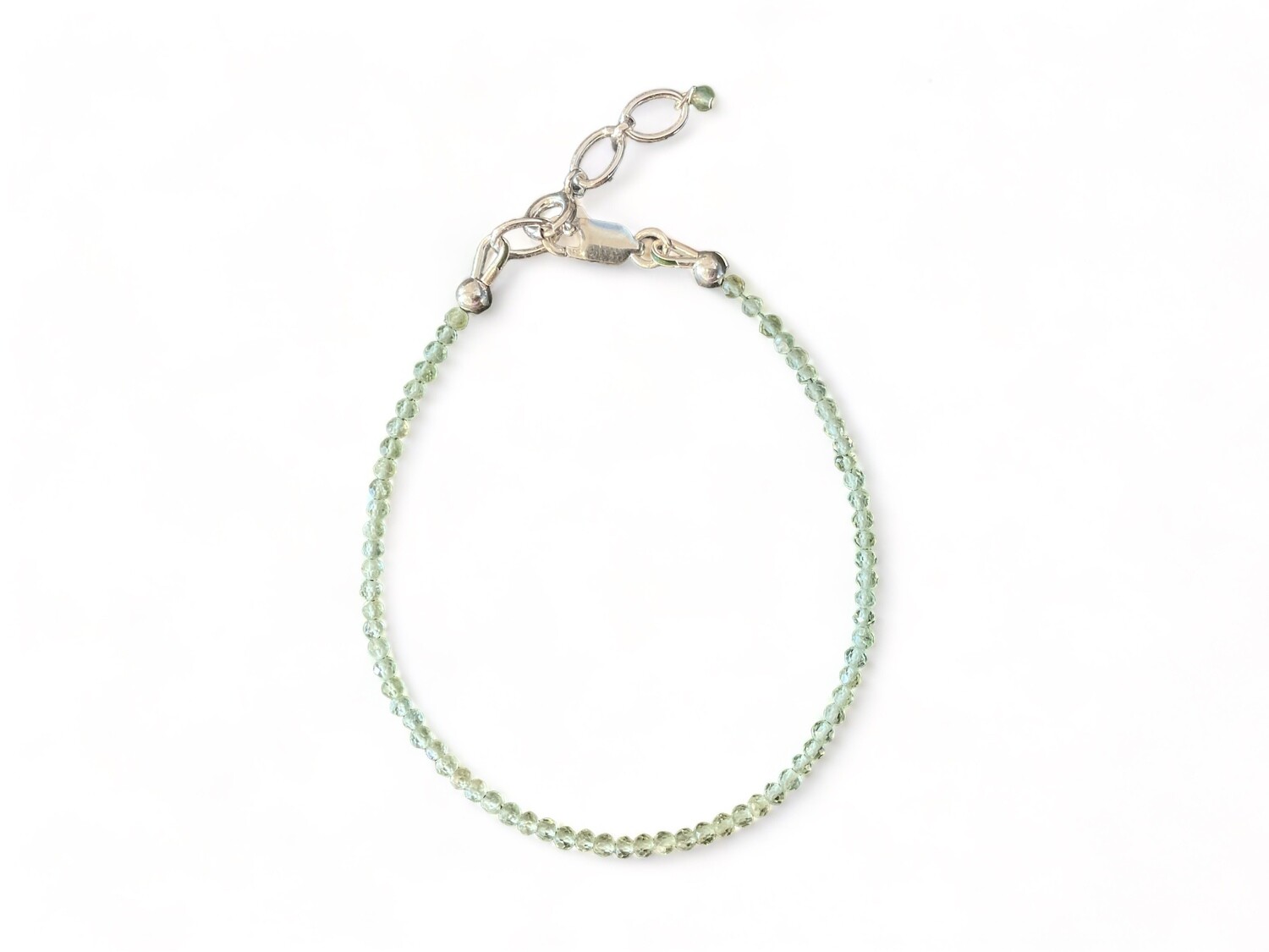 Image of a bracelet made of tiny 2mm micro-faceted green apatite beads, which are a bright green color. The bracelet features a sterling silver clasp and extender, designed to support manifestation and enhance sociability.