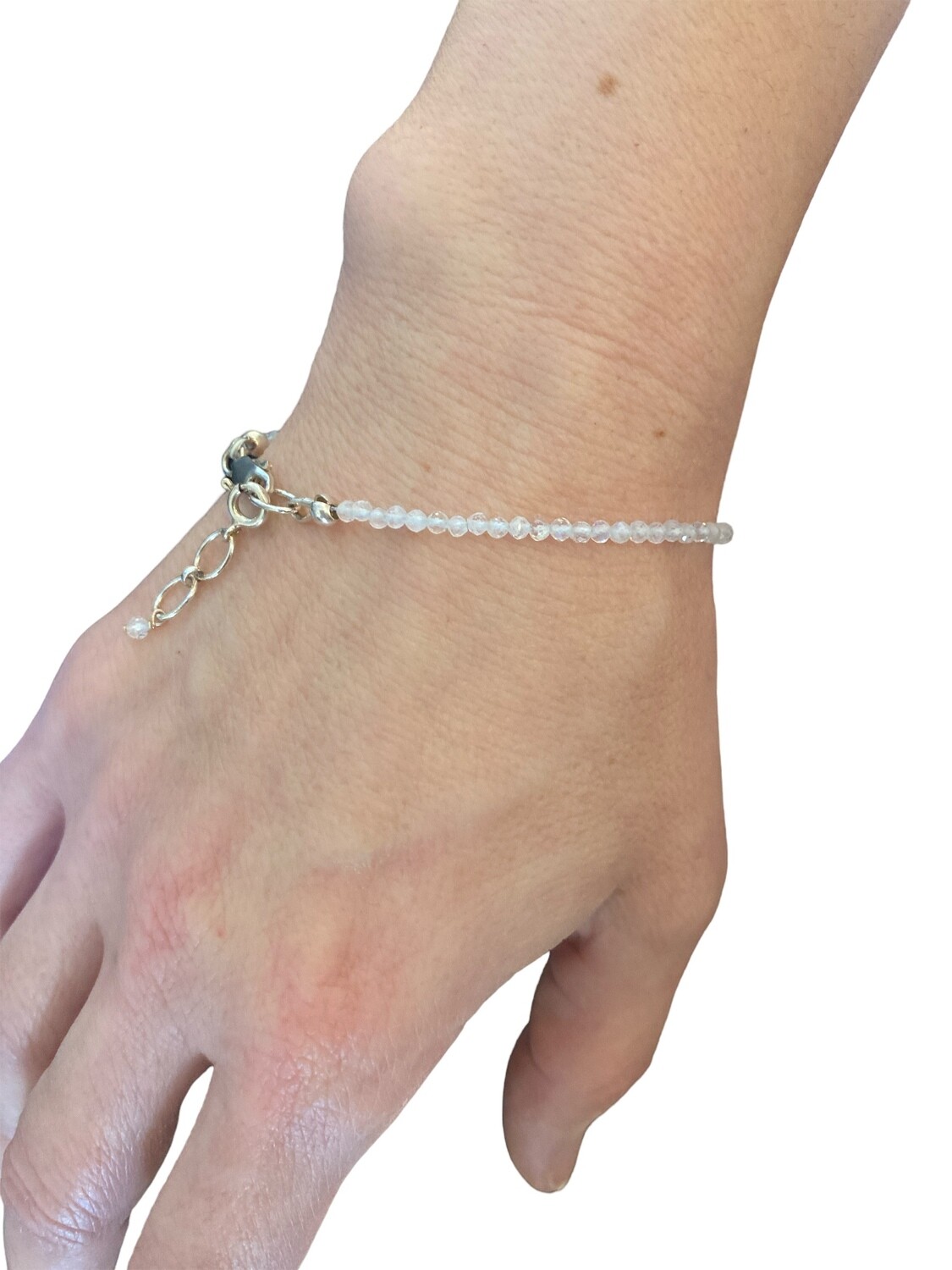 Photo of a Rainbow Moonstone bracelet with micro-faceted crystals. The bracelet features shimmering, multi-colored moonstone gems that reflect light, offering a spiritual and refined touch.  It measures 6.5 inches long with a 1 inch sterling silver extender chain.