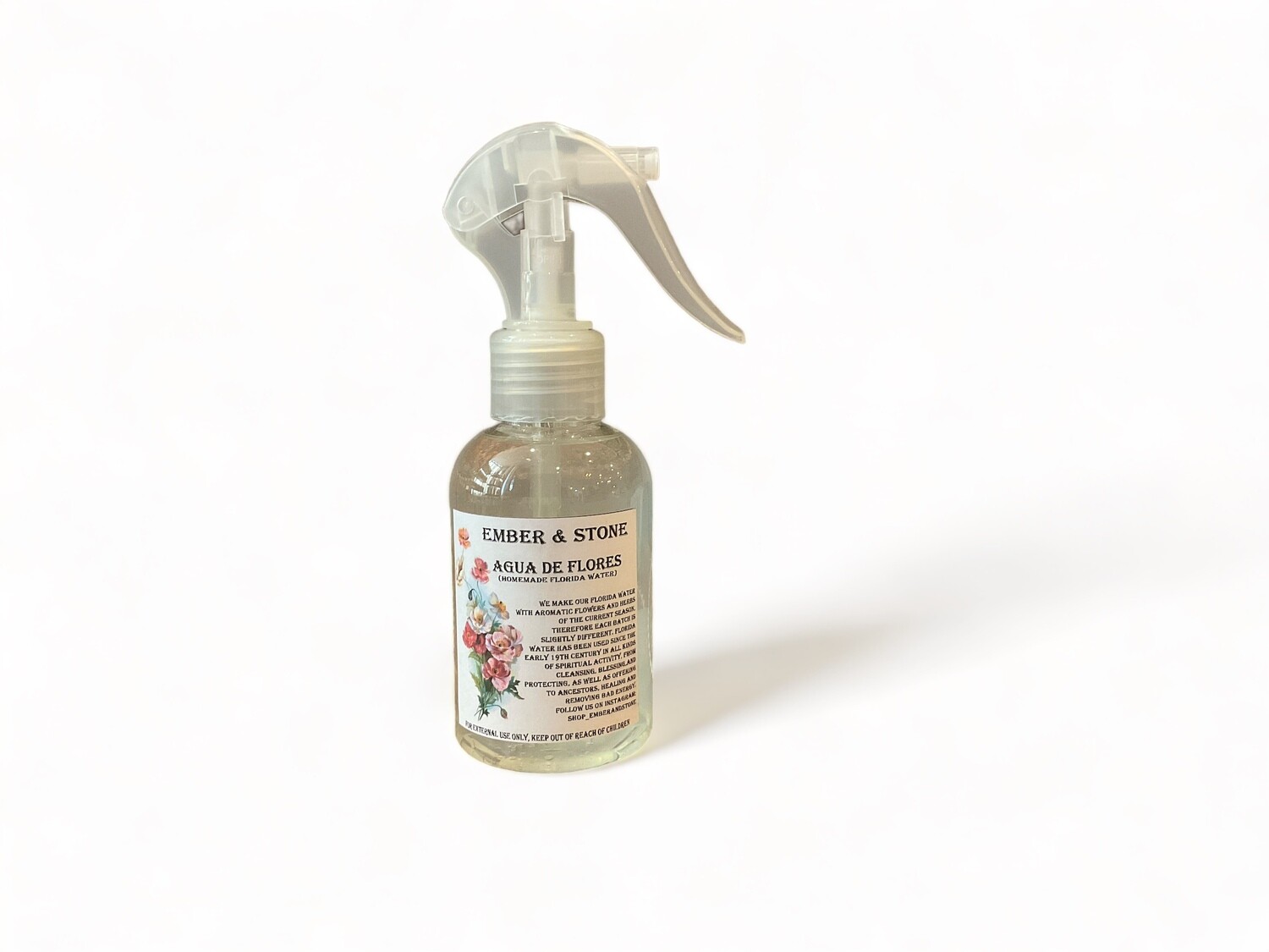 Image of a spray bottle labeled &#39;Agua de Flores&#39;. The bottle contains a light, transparent liquid and is topped with a simple spray nozzle. The label highlights that this is a homemade Florida water spray made from seasonal flowers and herbs, intended for cleansing, blessing, and protection. The fragrance of the spray changes with each season, reflecting its natural ingredients.