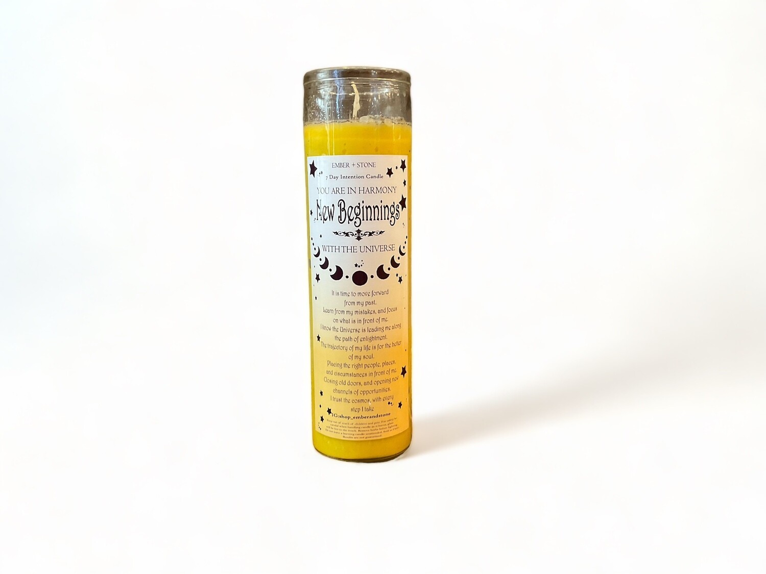 A slender glass jar containing a New Beginnings Intention Candle, featuring a label with &#39;New Beginnings Intention Candle in Skinny Glass Jar | LA&#39; and a description promoting renewal and positivity through its design.