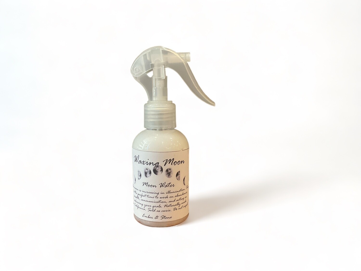 Waxing Moon Spray two ounce bottle labeled &#39;Waxing Moon Spray&#39;. The spray is designed to enhance focus on goals and harness the energy of illumination. The bottle features a label with a lunar motif, highlighting its use during the waxing moon phase. Ideal for promoting abundance and growth, the mist can be used to energize spaces and personal intentions.