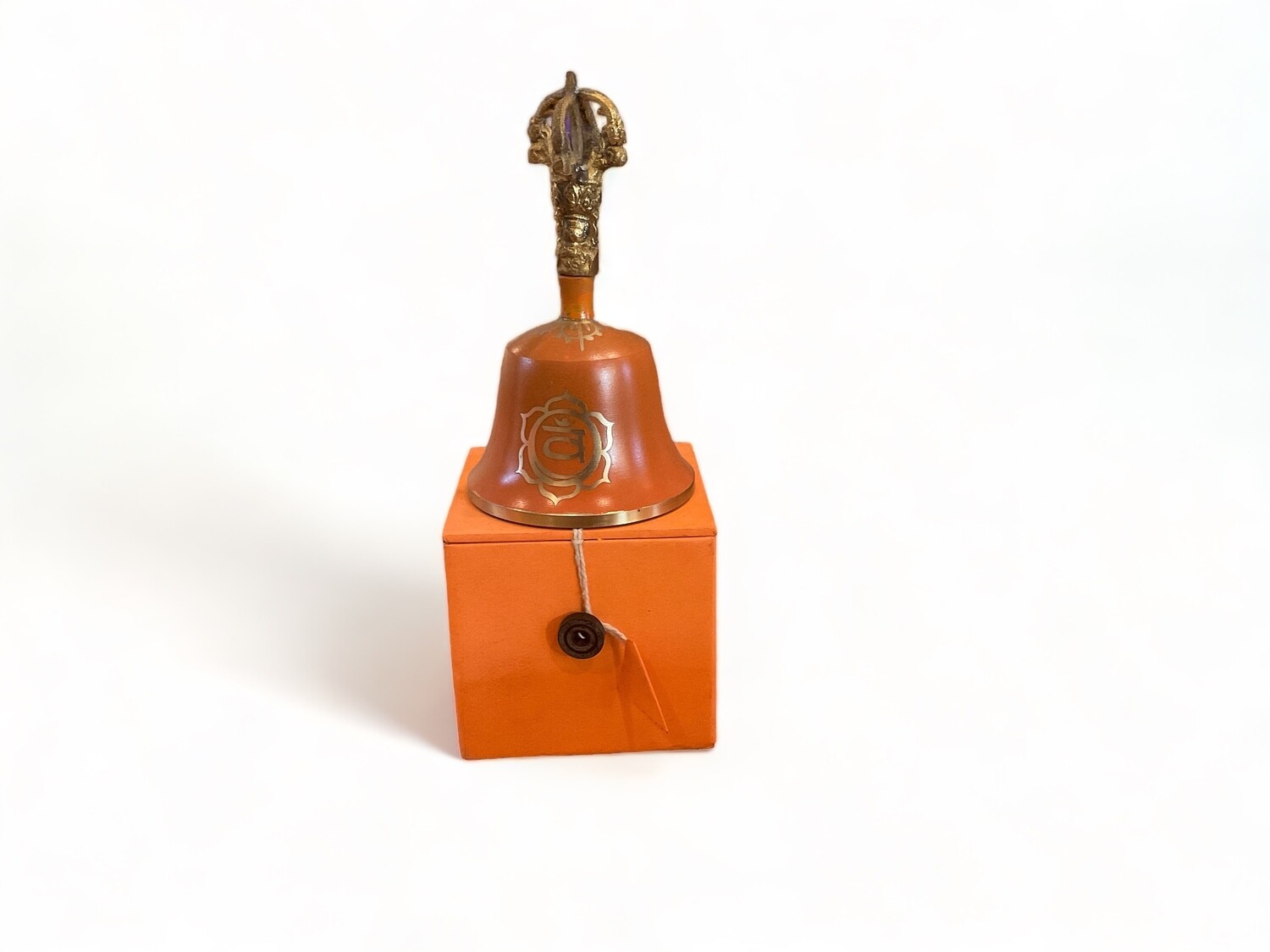 Photograph of an Orange Sacral Chakra Tibetan Bell, 5.5 inches, with a striker. The bell features a vibrant orange color with golden detailing. It produces a distinct, resonant sound when struck. Designed to clear space and balance the sacral chakra, this bell enhances creativity and sensuality.