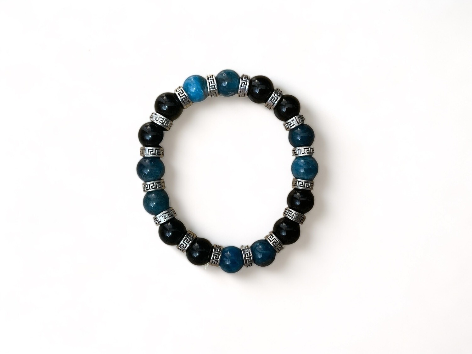 An image of a 10mm bracelet featuring matte black onyx beads interspersed with blue apatite stones. This piece is designed for protection, focus, and spiritual growth.