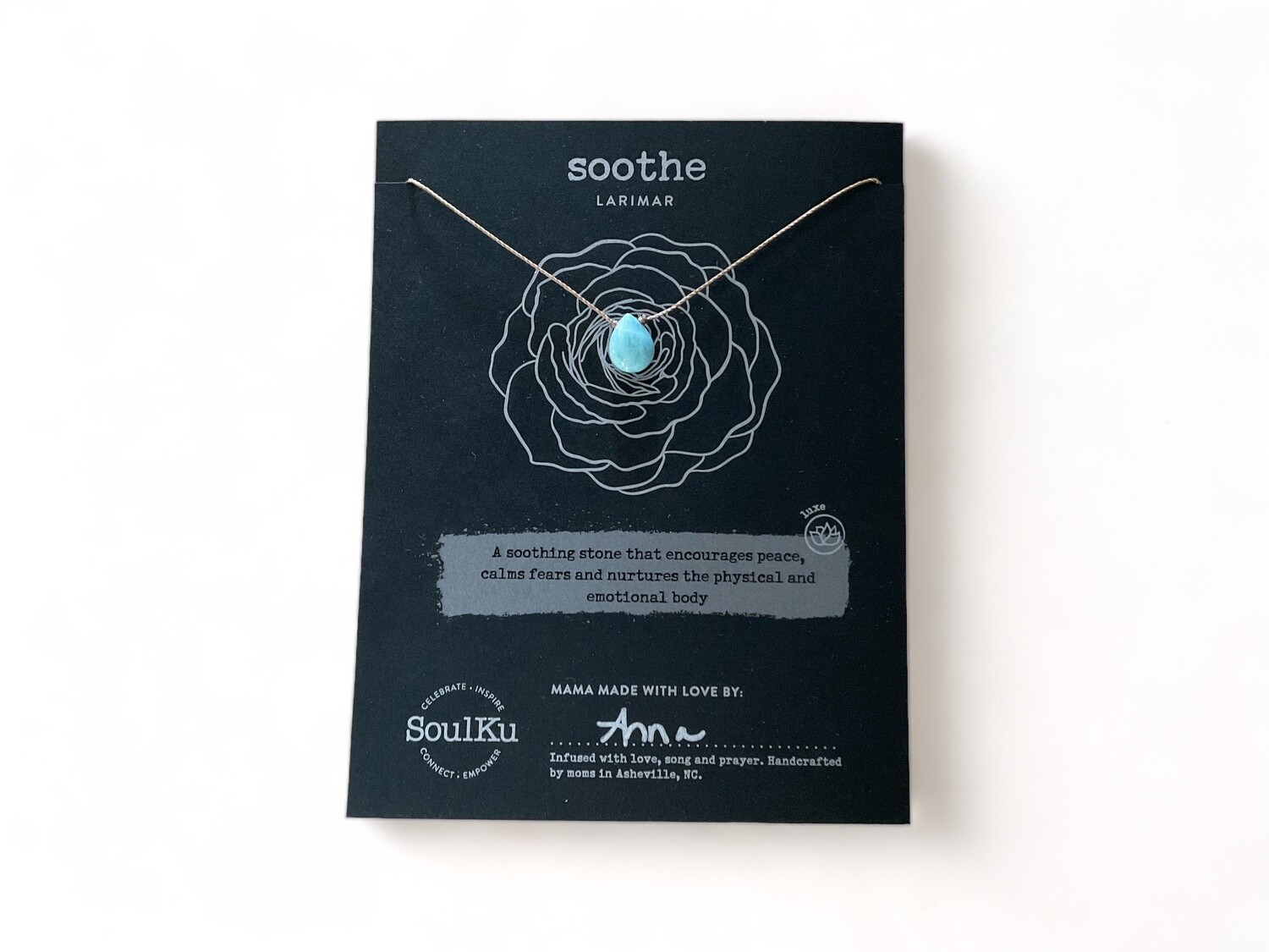 Photo depicts a Luxe Larimar Crystal Intention Necklace with a polished rare blue gemstone featuring a range of oceanic patterns. The necklace&#39;s cool hues and calming design are intended to promote relaxation and peace.