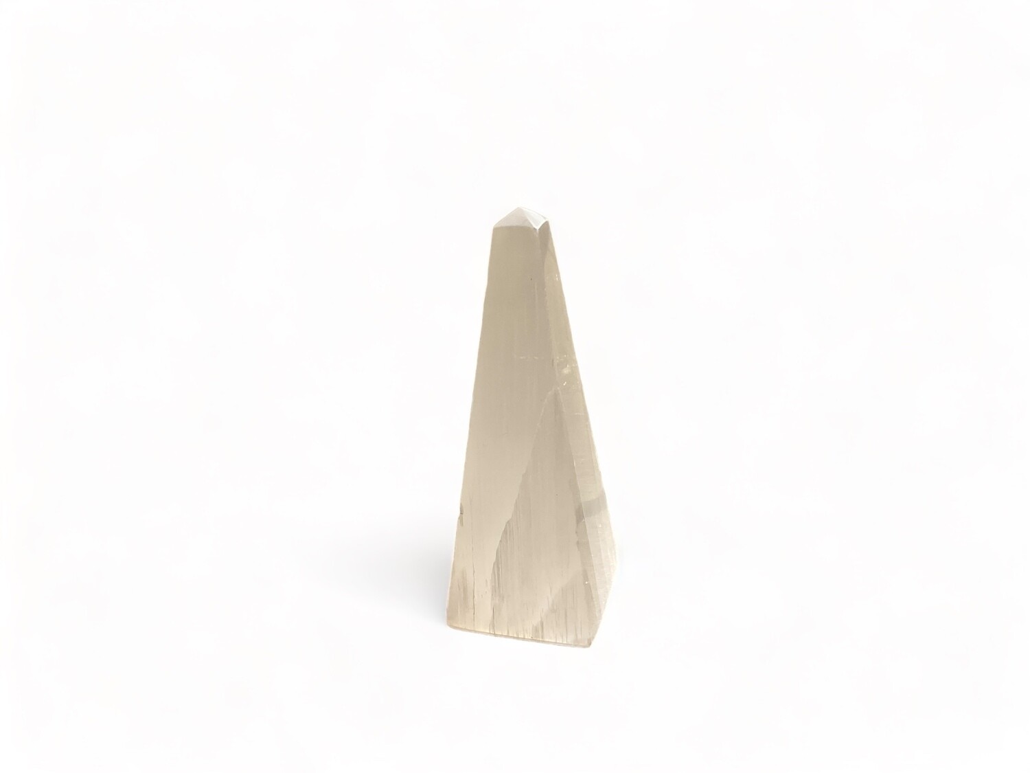 Image of a 4” Selenite obelisk crystal, perfect for energy cleansing and crystal grids. Ideal for enhancing spiritual growth, makes a great gift for crystal collectors, has a sleek, elegant design. Disclaimer: Stone color, size, or shape may slightly vary from image. Each order is randomly chosen by The Crystal Shrine staff.