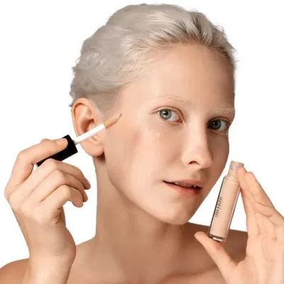 Close-up of a woman applying LORD &amp; BERRY liquid concealer to her face with a precise applicator. The image highlights beauty and makeup techniques for achieving a flawless, natural-looking complexion. Explore premium cosmetics at mygeishamiltonkeynes.co.uk. #LORDandBERRY #LiquidConcealer #FlawlessSkin