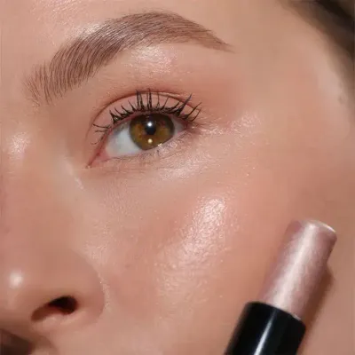 Close-up of a person applying LORD &amp; BERRY shimmering highlighter to their cheekbones, emphasizing a luminous, radiant makeup look. The image captures the smooth application and glowing finish, ideal for beauty tutorials and showcasing premium cosmetic products. Explore LORD &amp; BERRY at mygeishamiltonkeynes.co.uk. #LORDandBERRY #Highlighter #RadiantSkin