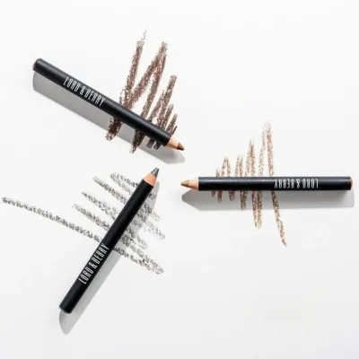 Close-up of three LORD &amp; BERRY eye pencils in varying shades, displayed alongside swatches on a clean white background. The image showcases the precision, smooth texture, and rich pigmentation of each pencil, ideal for defining eyes with long-lasting color. Shop the LORD &amp; BERRY eye pencil collection at mygeishamiltonkeynes.co.uk. #LORDandBERRY #EyePencil #MakeupEssentials