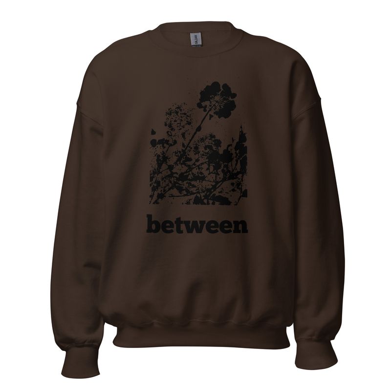Close-up of Between floral impression artwork on sweatshirt | Chocolate brown with black floral imprint | Front side