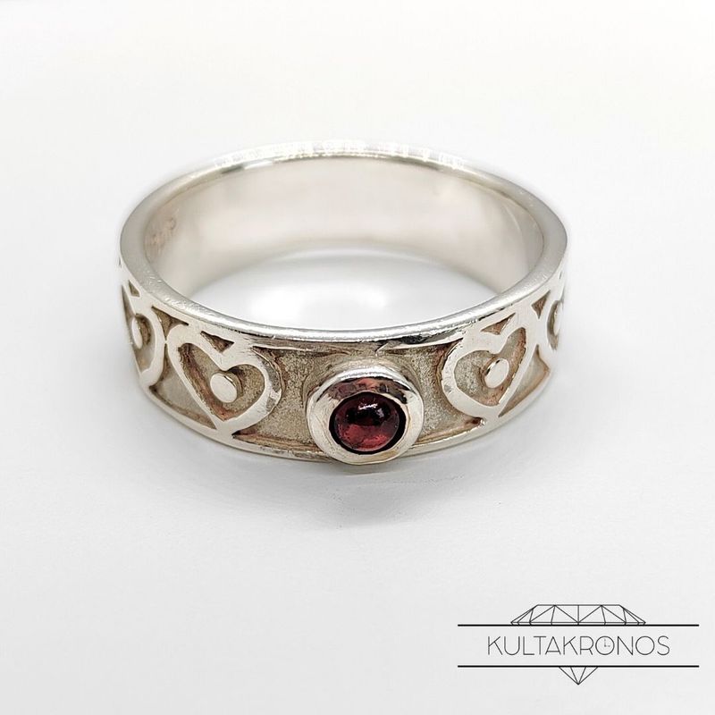 Sydänsormus punaisella kivellä